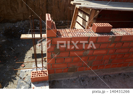 Brick wall construction in progress at a building site during daylight hours 140431266