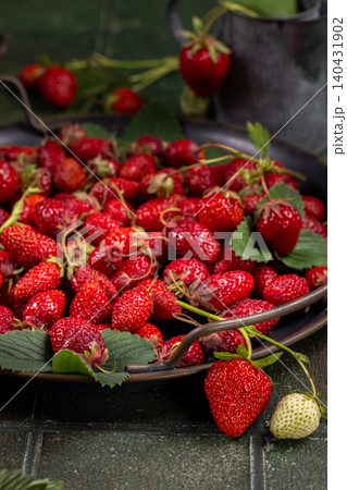 Freshly picked red strawberries overflowing a metal tray 140431902
