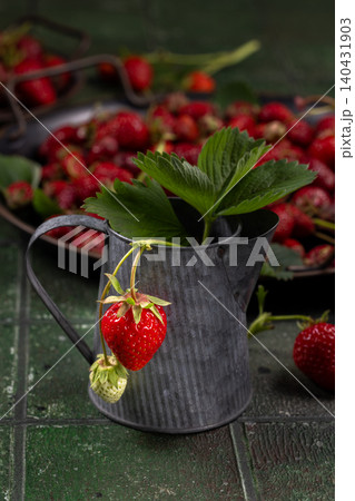 Fresh strawberries with leaves in rustic metal pitcher Fresh strawberries with leaves in rustic metal pitcher 140431903