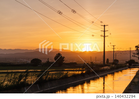 Sunset over irrigation canal and power lines in Ebro Delta Natural Park, Catalonia, Spain 140432294
