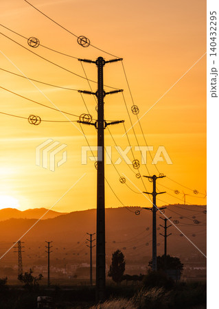 Power transmission lines and utility poles at sunset symbolizing rural electrification and energy distribution infrastructure 140432295