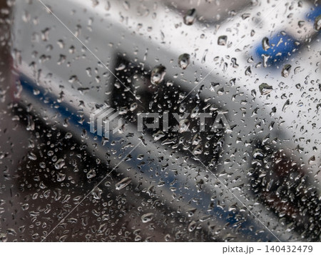 Emergency service vehicle in blur behind glass covered with rain drops in gray weather 140432479