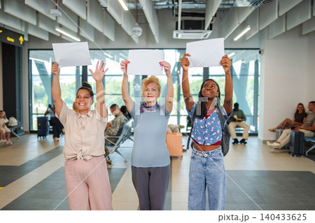 Diverse women holding blank signs in airport terminal greeting travelers Diverse women holding blank signs in airport terminal greeting travelers 140433625