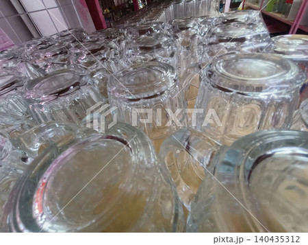 Glass cup row closeup on shelf, clear drinkware in market display Glass cup row closeup on shelf, clear drinkware in market display 140435312