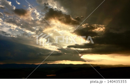雲と光条が印象的な北海道美瑛町の丘の上から見た夕暮れの風景 雲と光条が印象的な北海道美瑛町の丘の上から見た夕暮れの風景 140435355