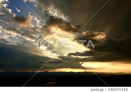 雲と光条が印象的な北海道美瑛町の丘の上から見た夕暮れの風景 雲と光条が印象的な北海道美瑛町の丘の上から見た夕暮れの風景 140435358