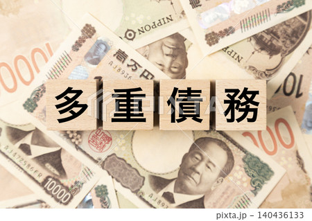 「多重債務」と書かれたブロックとたくさんの一万円札 「多重債務」と書かれたブロックとたくさんの一万円札 140436133