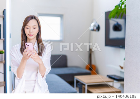 リビングでスマートフォンを見る女性 140436188