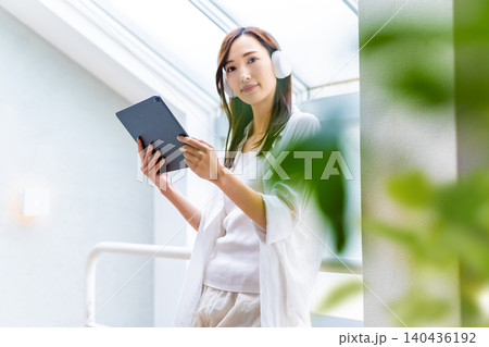 タブレットとヘッドホンでくつろぐ女性 タブレットとヘッドホンでくつろぐ女性 140436192