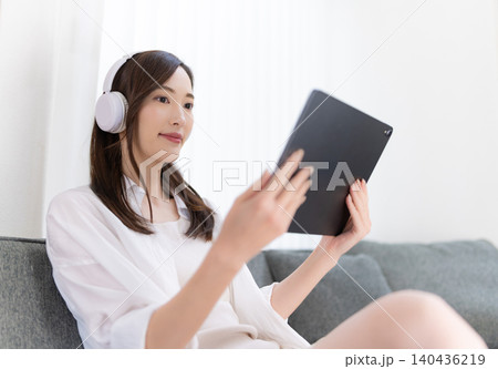 ソファでタブレットとヘッドホンを楽しむ女性 ソファでタブレットとヘッドホンを楽しむ女性 140436219