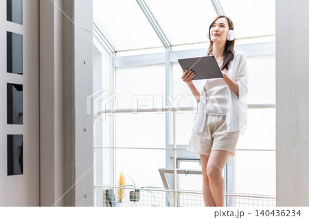 タブレットとヘッドホンでくつろぐ女性 タブレットとヘッドホンでくつろぐ女性 140436234