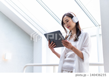 タブレットとヘッドホンで情報収集する女性 140436235