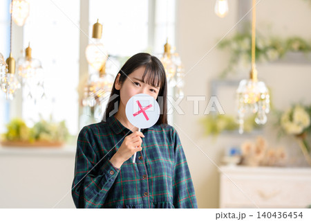 バツの札を手に持つ若い女性 140436454