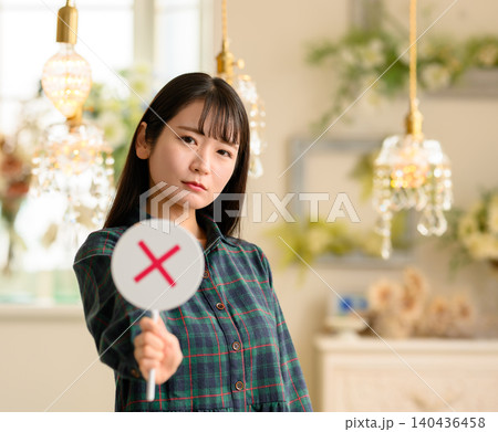 バツ印の札を掲げる若い女性 バツ印の札を掲げる若い女性 140436458