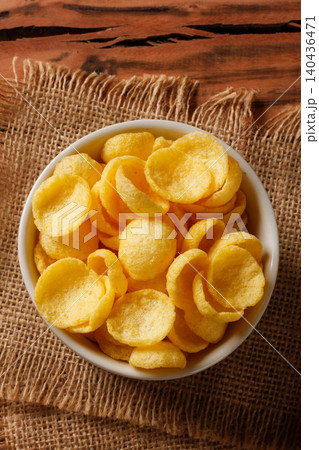 Crunchy corn snack chips in white ceramic bowl on burlap cloth over rustic wooden table Crunchy corn snack chips in white ceramic bowl on burlap cloth over rustic wooden table 140436471