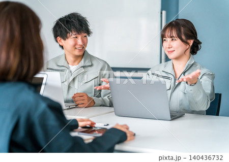 オフィス,事務所でミーティング,会議で説明をする作業着姿の女性従業員 オフィス,事務所でミーティング,会議で説明をする作業着姿の女性従業員 140436732