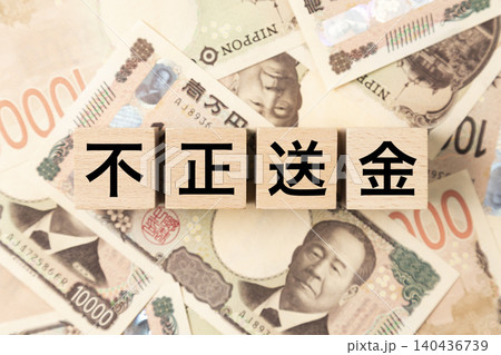 「不正送金」と書かれたブロックとたくさんの一万円札 140436739