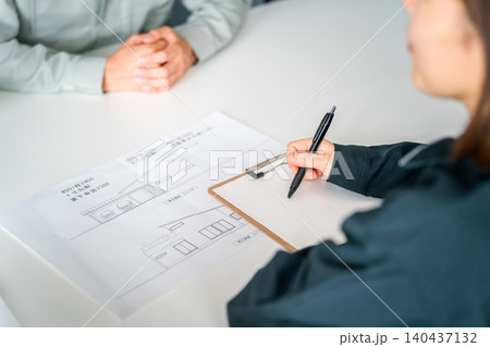 マイホームの図面を見ながら会議,打ち合わせ,商談する作業服姿の女性の手元 マイホームの図面を見ながら会議,打ち合わせ,商談する作業服姿の女性の手元 140437132