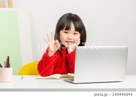 A cheerful young student showing an okay sign gesture while studying with a laptop at home. A cheerful young student showing an okay sign gesture while studying with a laptop at home. 140440844