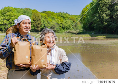 収穫した農産物を手に微笑むシニア夫婦と日本の田園風景 収穫した農産物を手に微笑むシニア夫婦と日本の田園風景 140441019