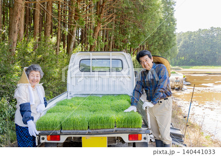 田植え用の稲苗を積んだ軽トラックと笑顔のシニア夫婦 140441033