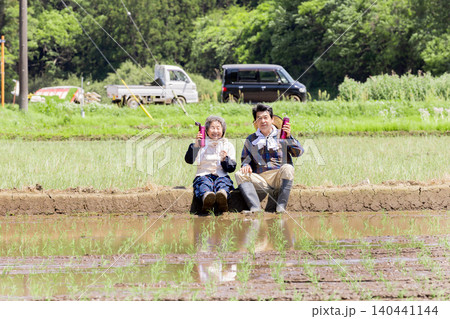 田植え作業の合間に休憩する笑顔のシニア夫婦 140441144