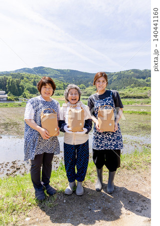 収穫した農産物を手に田んぼで微笑む三世代の日本人女性 収穫した農産物を手に田んぼで微笑む三世代の日本人女性 140441160