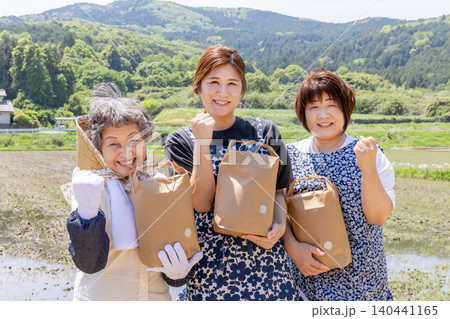 日本の農村で収穫した農産物を手に笑顔でガッツポーズする三世代女性 140441165