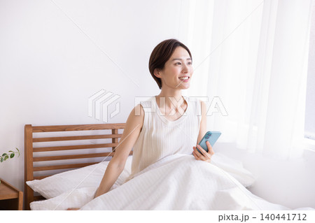 朝 ベッドでスマホを見る女性 朝 ベッドでスマホを見る女性 140441712