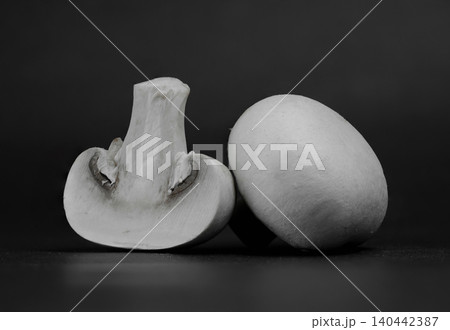 Low-key studio shot of fresh agaricus bisporus mushrooms, one halved showing internal structure Low-key studio shot of fresh agaricus bisporus mushrooms, one halved showing internal structure 140442387
