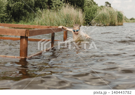dynamic, relaxed shot boy jumping into natural lake. child is captured mid flight, creating sense excitement. image perfect family vacations, water safety, promoting active lifestyle among children dynamic, relaxed shot boy jumping into natural lake. child is captured mid flight, creating sense excitement. image perfect family vacations, water safety, promoting active lifestyle among children 140443782