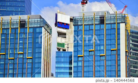 Crane on the construction site in a site surrounded by the high buildings. Office building under construction in the vicinity of high apartment buildings and office building. 140444568