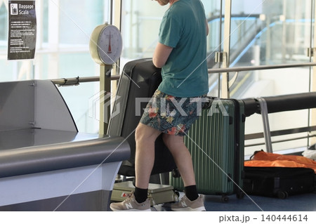 空港のチェックイン前に荷物の重量を計る乗客 空港のチェックイン前に荷物の重量を計る乗客 140444614