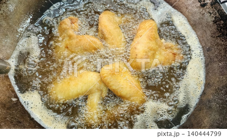 Crispy Golden Chicken Wings Deep Frying in Hot Oil in a Wok Crispy Golden Chicken Wings Deep Frying in Hot Oil in a Wok 140444799