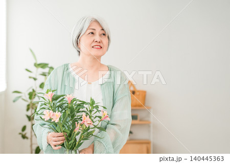 自宅のリビングで花をいけるシニア女性(フラワーセラピー,フラワーアレンジメント)) 自宅のリビングで花をいけるシニア女性(フラワーセラピー,フラワーアレンジメント)) 140445363