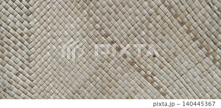 A traditional woven palm leaf mat featuring a delicate geometric diamond pattern. A traditional woven palm leaf mat featuring a delicate geometric diamond pattern. 140445367