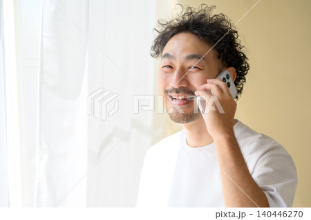 窓際でスマートフォンで通話する日本人男性 窓際でスマートフォンで通話する日本人男性 140446270