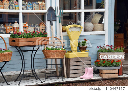 Colorful garden shop display with potted flowers, wooden crates and vintage scale outside storefront 140447167