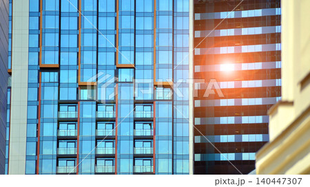 Modern office building with glass facade on a clear sky background. Transparent glass wall of office building. Modern office building with glass facade on a clear sky background. Transparent glass wall of office building. 140447307
