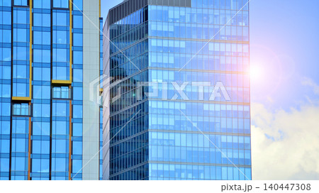 Modern office building with glass facade on a clear sky background. Transparent glass wall of office building. Modern office building with glass facade on a clear sky background. Transparent glass wall of office building. 140447308