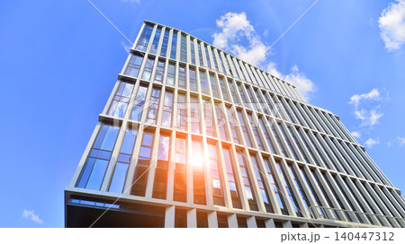 Modern office building with glass facade on a clear sky background. Transparent glass wall of office building. Modern office building with glass facade on a clear sky background. Transparent glass wall of office building. 140447312