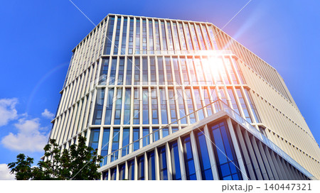 Modern office building with glass facade on a clear sky background. Transparent glass wall of office building. Modern office building with glass facade on a clear sky background. Transparent glass wall of office building. 140447321