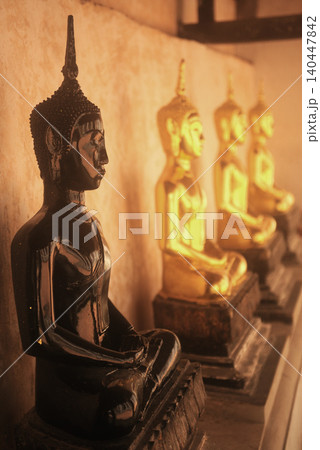 The ancient Buddha images are lined up in the cloister on a Church of Wat Khanon, which also serves as a venue for traditional Thai shadow puppet shows in Thailand. The ancient Buddha images are lined up in the cloister on a Church of Wat Khanon, which also serves as a venue for traditional Thai shadow puppet shows in Thailand. 140447842
