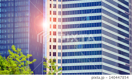 Modern office building with glass facade on a clear sky background. Transparent glass wall of office building. Modern office building with glass facade on a clear sky background. Transparent glass wall of office building. 140447854