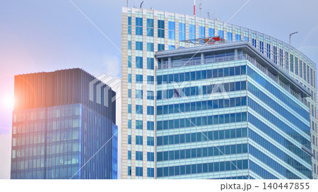 Modern office building with glass facade on a clear sky background. Transparent glass wall of office building. Modern office building with glass facade on a clear sky background. Transparent glass wall of office building. 140447855
