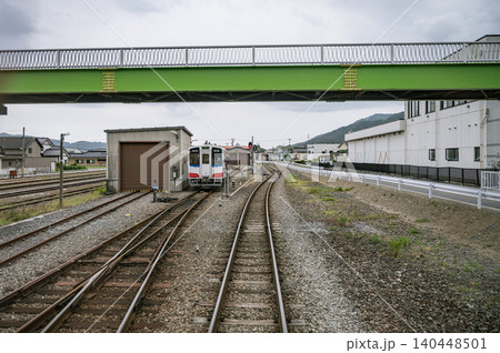 鮮やかなグリーンの跨線橋の下に佇む地方鉄道の列車と車両基地の風景 鮮やかなグリーンの跨線橋の下に佇む地方鉄道の列車と車両基地の風景 140448501