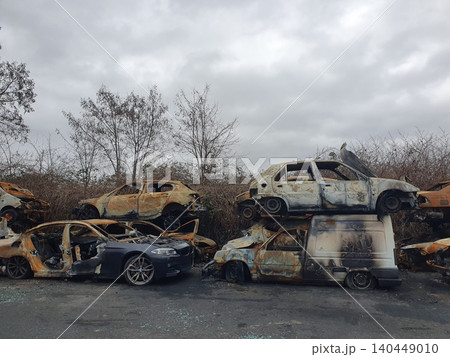 Stacked Burnt Cars And Abandoned Vehicles In Overgrown Scrapyard With Urban Decay Mood 140449010