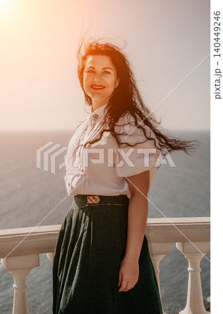 Woman sunset sea enjoying warm golden light on a balcony overlooking the ocean during a peaceful summer vacation trip Woman sunset sea enjoying warm golden light on a balcony overlooking the ocean during a peaceful summer vacation trip 140449246