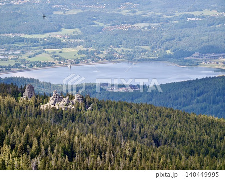 Forested mountain ridge with rocky outcrops overlooking a lake and valley Forested mountain ridge with rocky outcrops overlooking a lake and valley 140449995