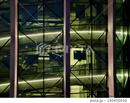 Modern glass facade with illuminated interior ramps and structural steel grid 140450030
